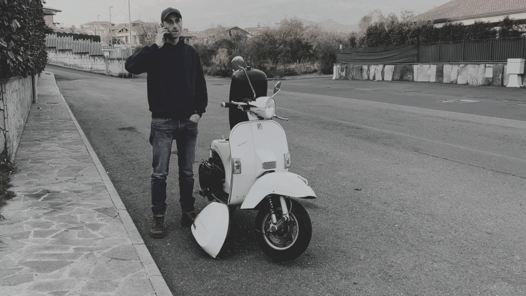 Vespista fermo a bordo strada con la Vespa in panne